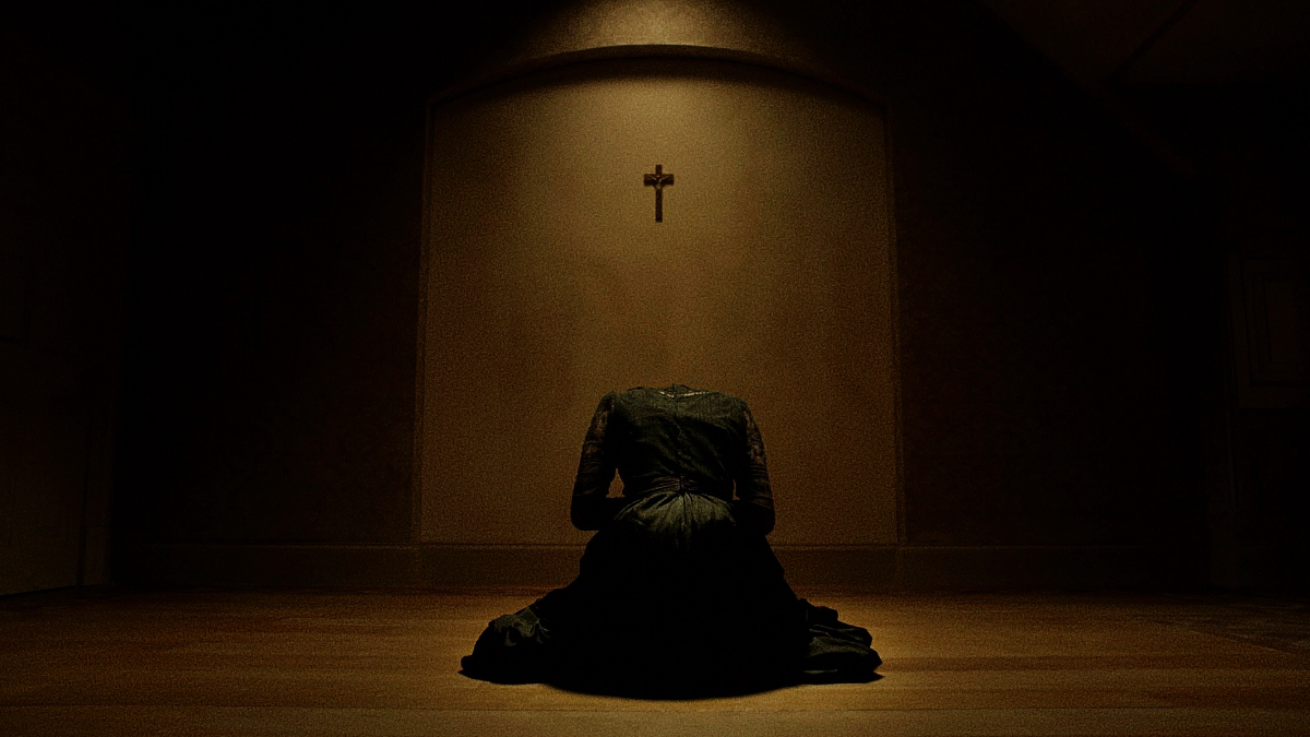 Vanessa Ives kneeling alone before a small crucifix in a dim interior, illuminated by a single warm light from above