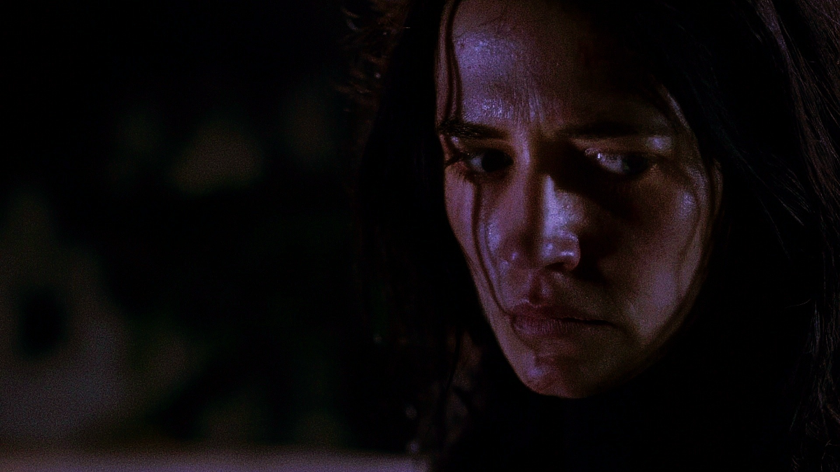 Close portrait of Vanessa in cool blue and violet light, eyes lowered, listening to something the camera cannot see
