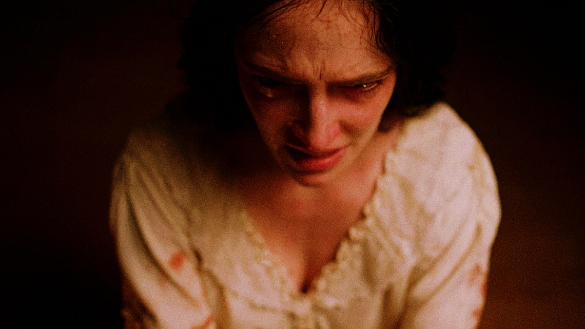 A close portrait of Vanessa in white nightclothes, tear-streaked and lucid, looking down after a long ordeal